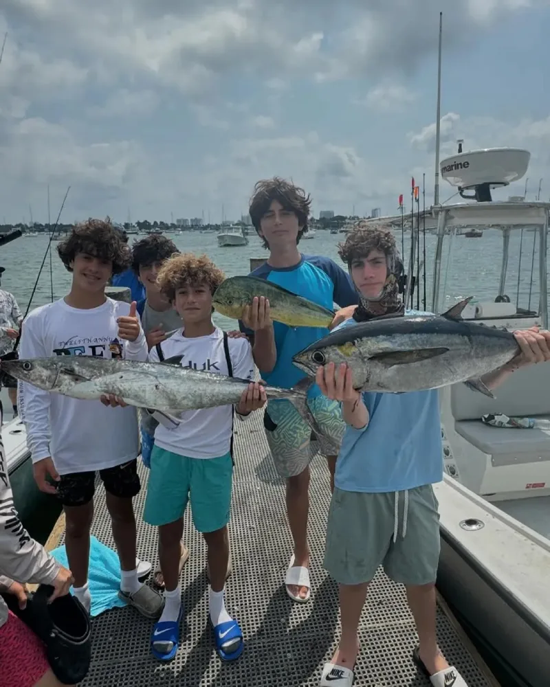 Family enjoying a private fishing charter in Miami, kids reeling in fish and smiling on the boat
